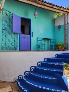 a house with blue stairs in front of a building at Chalé Flor do Ser in Canoa Quebrada