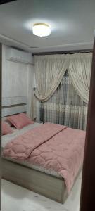 a bedroom with a bed with pink sheets and curtains at Apprtmt jury de luxe in Nador