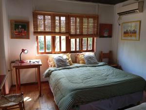 Un dormitorio con una cama y una mesa y ventanas. en cabaña los cardenales, en Gualeguaychú
