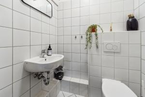 オッフェンバッハにあるApartment Ledermuseumの白いタイル張りのバスルーム(洗面台、トイレ付)