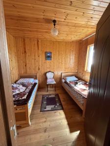 a room with two beds and a chair in a cabin at Bata GuesThouse in Adishi