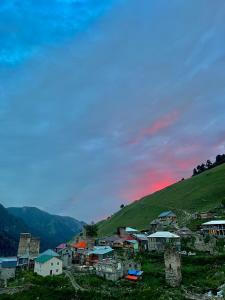 a village on a hill with the sunset in the background at Bata GuesThouse in Adishi