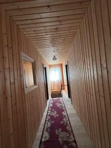 a hallway with a rug in a room with wooden walls at Bata GuesThouse in Adishi