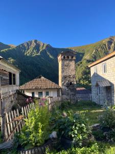 a garden in front of a house with mountains in the background at Bata GuesThouse in Adishi