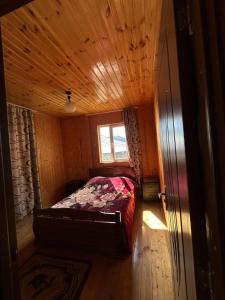 a bedroom with a bed in a wooden room at Bata GuesThouse in Adishi