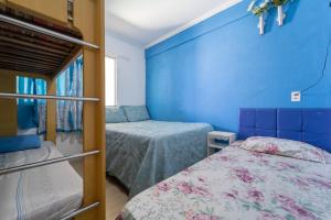 Un dormitorio con dos camas y una pared azul. en Apto com Wi-Fi a 950m da Praia da Tartaruga, en Rio das Ostras