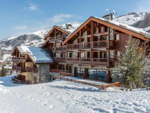 a log home in the snow with mountains in the background at Appt 6pers avec piscine, spa, parking, animaux admis - FR-1-461-28 in Saint-Martin-de-Belleville