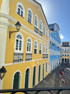 a yellow building with white windows on a street at Pousada Cores do Pelô in Salvador