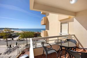 a balcony with a table and chairs and the beach at Apartamento Praia da Rocha in Portimão