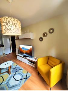 a living room with a yellow couch and a tv at Apartamento Punta Escarra in Escarrilla