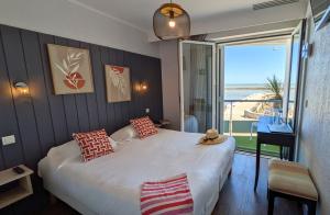 a bedroom with a large bed with a view of the ocean at Logis Hôtel de La Marée - Face à l'océan - Ile de Ré in Rivedoux-Plage