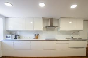 a white kitchen with white cabinets and a sink at Cal badia in Vilallovent