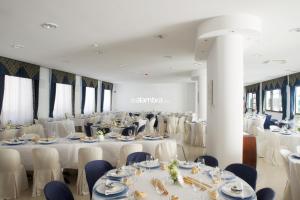 - une salle de banquet avec des tables et des chaises blanches dans l'établissement Il Convento, à Trino