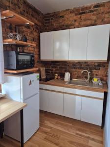 a kitchen with white cabinets and a brick wall at Apartament Szadoka - Katowice, Free Parking in Katowice