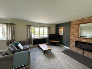 a living room with a couch and a fireplace at Fallow View - Luxury Countryside Cottage in Coughton
