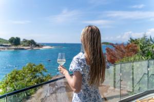 a woman holding a glass of wine overlooking the ocean at Manta Hotel in Ksamil