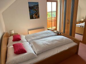 a bed with two red pillows on top of it at Villa Sara - Wörtherseeblick, Skifahren, Sauna in Sankt Bartlmä