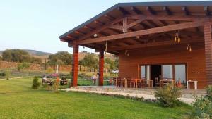 a wooden cabin with tables and chairs in a yard at Tenuta Soria Location immersa nel verde con piscina privata in Frassino