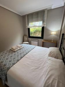 a bedroom with a large white bed with a window at Gestiona2R - Apartamento en el casco antiguo Llanisco in Llanes