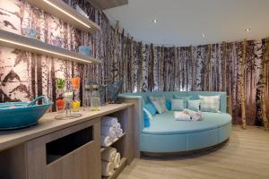 a room with a blue couch in front of a wall at Landidyll Hotel Haus Hochstein in Wenholthausen