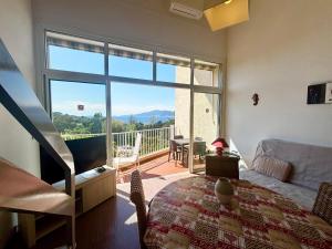 ein Wohnzimmer mit Tisch und großem Fenster in der Unterkunft Casamea - Duplex, Vue mer, Plage à 100m, Clim in Porticcio