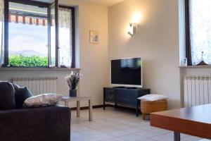 Una sala de estar con televisión y un sofá. en Appartamento Margherita, en Porto Valtravaglia