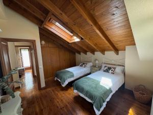 two beds in a large room with wooden ceilings at Casa de Robles Cantabria, en el corazón de los Valles Pasiegos in Sel de la Carrera