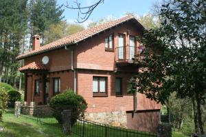 a brick house with a fence in front of it at Casa de Robles Cantabria, en el corazón de los Valles Pasiegos in Sel de la Carrera