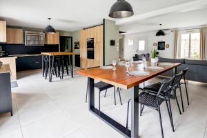 a kitchen and dining room with a wooden table and chairs at Maison Cosy Campagne, Spacieuse, Terrasse in Le Plessis-Feu-Aussoux