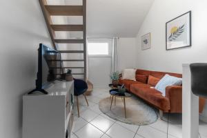 a living room with a couch and a tv at Résidence Gilbert - Appartements design centre ville in Vichy