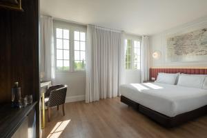 a hotel room with a bed and a desk and windows at Exe Zarzuela Park in Madrid