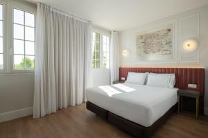 a bedroom with a large white bed and windows at Exe Zarzuela Park in Madrid +58 photos
