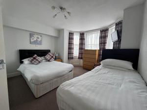 Una habitación de hotel con dos camas y dos ventanas. en Devonshire House Holiday Flats, en Eastbourne