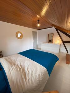 a bedroom with a blue and white bed with a wooden ceiling at Maison calme et chaleureuse au coeur du Béarn in Berenx