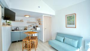 a living room with a blue couch and a kitchen at La Parenthèse Impressionniste in Limetz