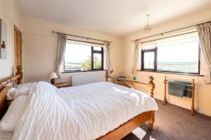 ein Schlafzimmer mit einem großen Bett und zwei Fenstern in der Unterkunft The Cottage - Holiday home in Reedham on the Southern Norfolk Broads in Reedham