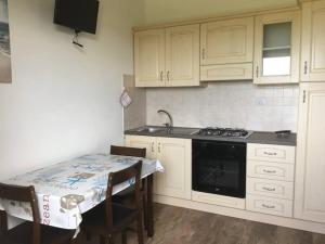 eine Küche mit Herd und Tisch mit Stühlen in der Unterkunft agriturismo gli olivastri, appartamento la rosa dei venti con piscina e solarium , vista mare ,climatizzatore ,wifi in Aglientu + 22 Fotos