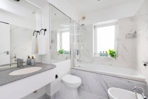 a white bathroom with a tub and a toilet and a sink at Excellent 3 bed House Hyde Park in London