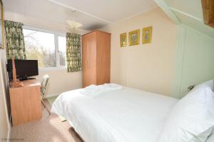 a bedroom with a white bed and a television at Bittern - Horning holiday home in Horning