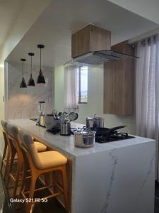 a kitchen with a counter with a stove and chairs at El rincón de Valentina in Pelileo