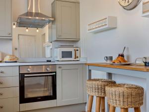 a kitchen with white cabinets and a counter with stools at 3 Bed in Montrose 90784 in Inverkeilor +17 photos
