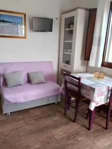 ein Wohnzimmer mit einem Tisch, einem Sofa, einem Tisch und einem Stuhl in der Unterkunft agriturismo gli olivastri, appartamento la rosa dei venti con piscina e solarium , vista mare ,climatizzatore ,wifi in Aglientu