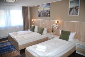 een hotelkamer met twee bedden met witte lakens bij D&D Hotel by Wiggers in Bad Oldesloe