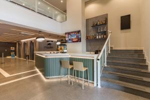 a bar with stools in a room with stairs at Cyclinn Faria Lima Itaim in São Paulo