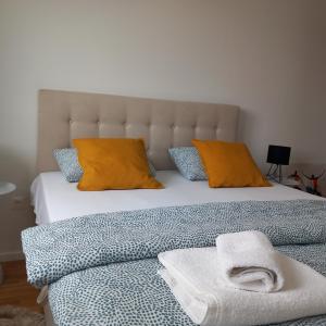 a bed with orange pillows and a towel on it at Apartment DIVA, private parking in Osijek