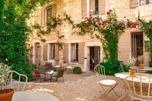 un patio extérieur avec tables, chaises et rosiers dans l'établissement La Maison du Village, à Saint-Rémy-de-Provence