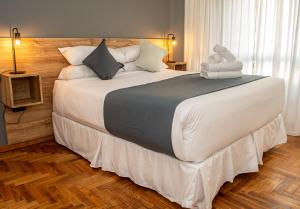 una habitación con una cama grande con sábanas y almohadas blancas en El Misti Suites Buenos Aires, en Buenos Aires