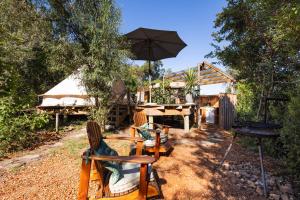a patio with chairs and an umbrella and a grill at Zen Valley Glamping in Plettenberg Bay