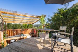 a patio with a table and chairs under a pergola at Zen Valley Glamping in Plettenberg Bay