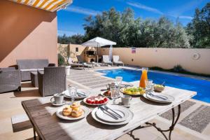 un tavolo con del cibo sopra accanto a una piscina di Leda by Vintage Travel a Città di Lefkada